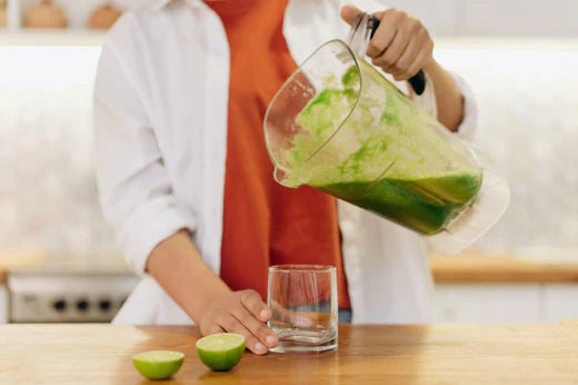 woman pouring green smoothie into glass